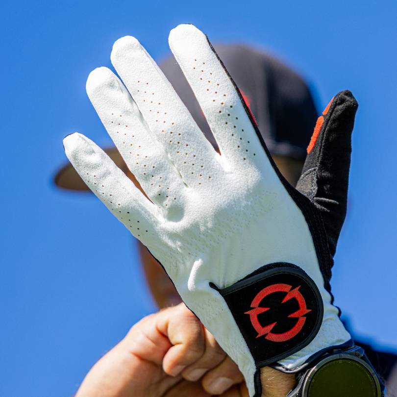 EXO golf glove  -  Golfer putting on the glove with back of hand showing red colorway logo on black palm