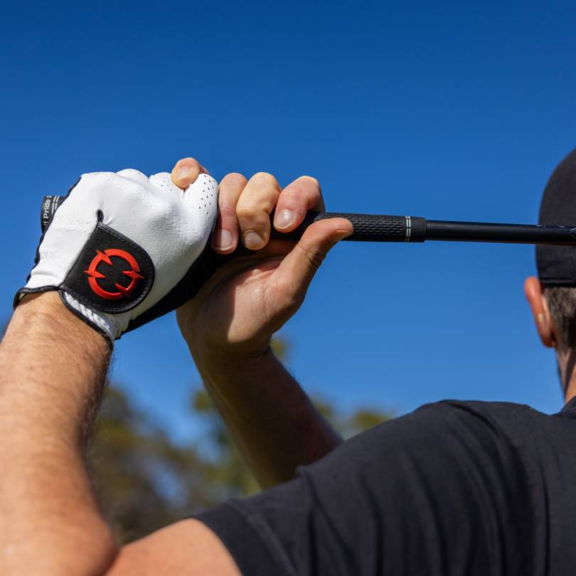 EXO golf glove - Golfer holding finished pose with a close up of the back of the hand of a glove with red logo showing