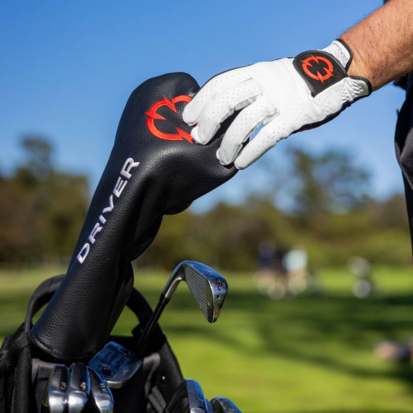 EXO golf glove - golfer wearing a red eco glove reaching for an EXO driver cover. 