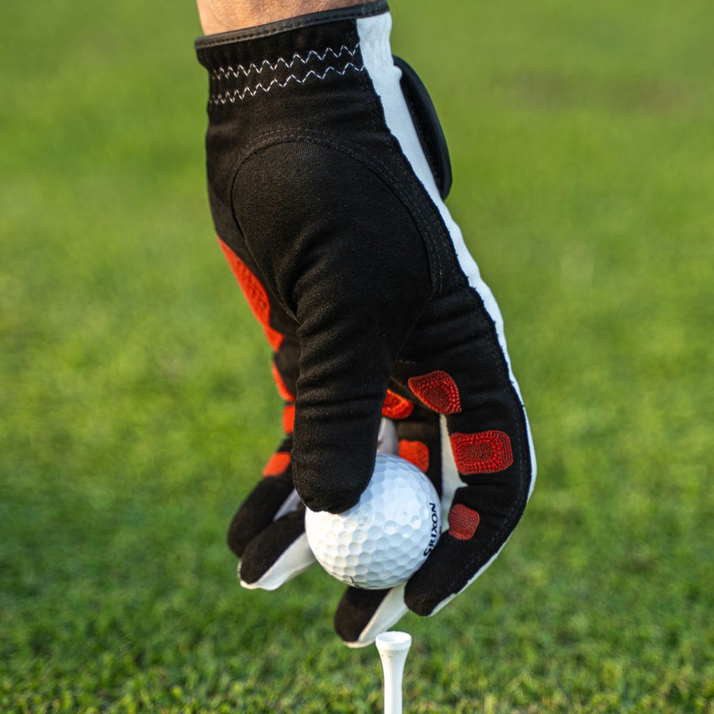 EXO Golf Glove with red nanocells putting a ball on a tee
