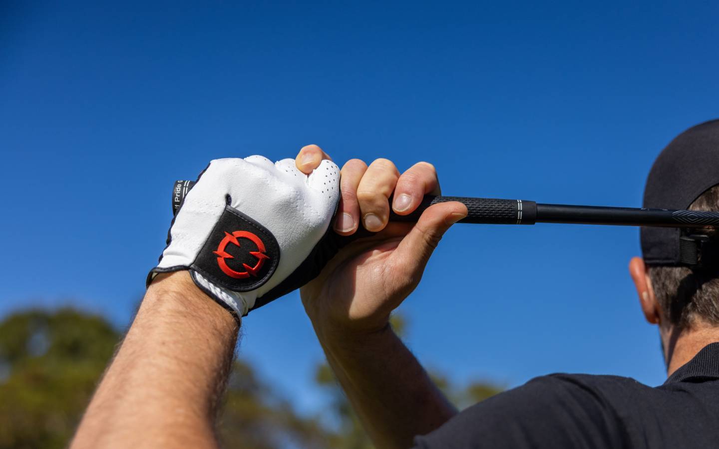 Golfer holding finishing pose with a EXO golf Glove visible with red logo